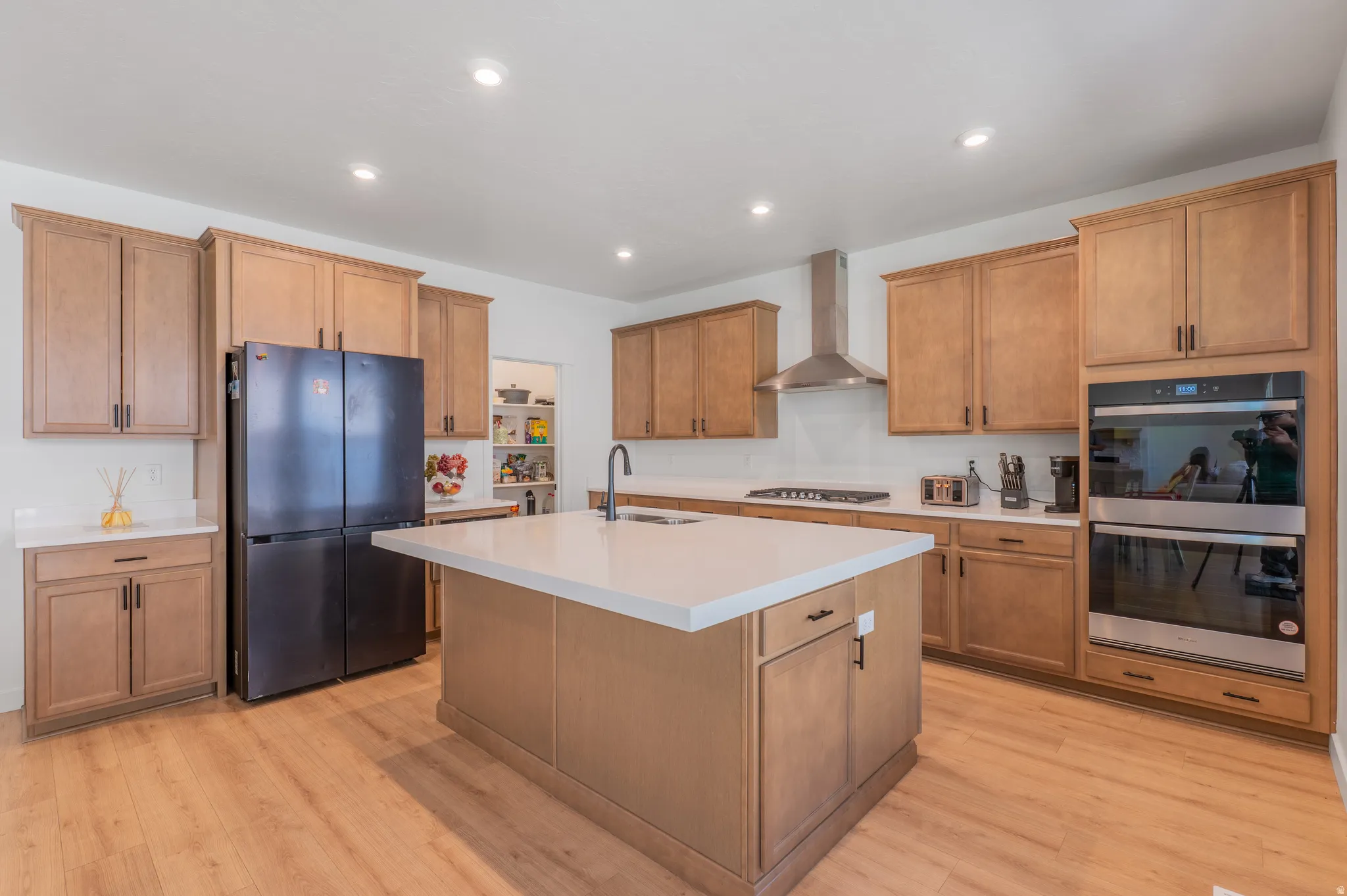 Kitchen featuring a central island with white countertop, wood-finish cabinetry, stainless steel appliances, and recessed lighting