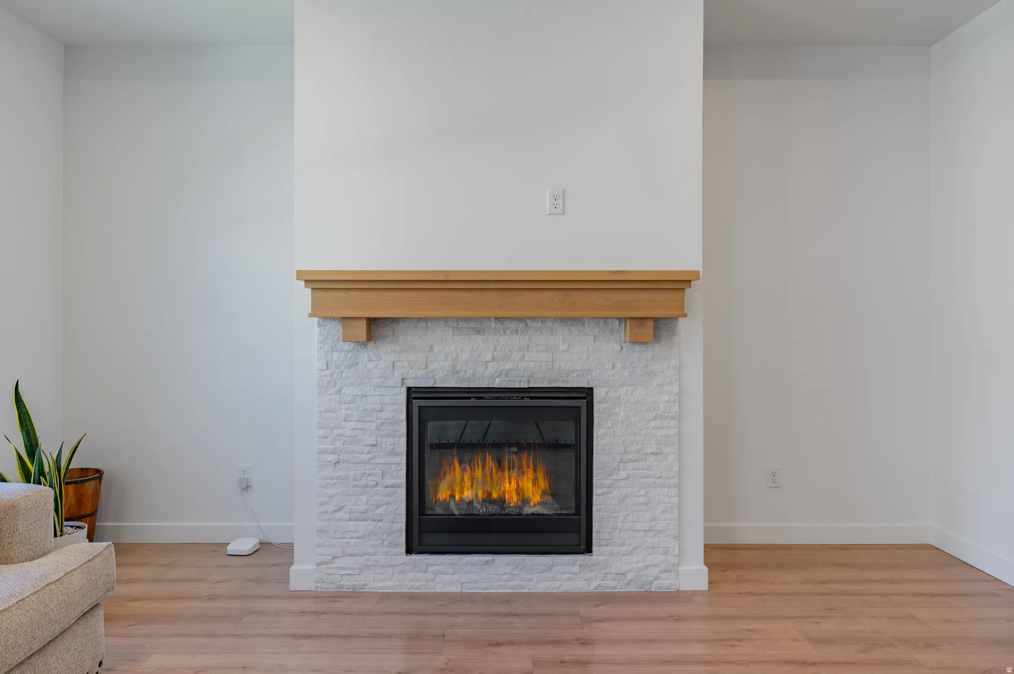 Recessed fireplace featuring a light-toned wood mantel and stacked stone surround