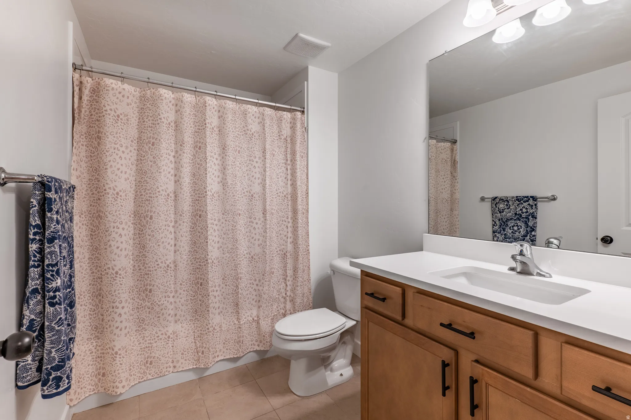 Bathroom featuring a wood-finish vanity with a white countertop, an integrated sink, and brushed nickel fixtures
