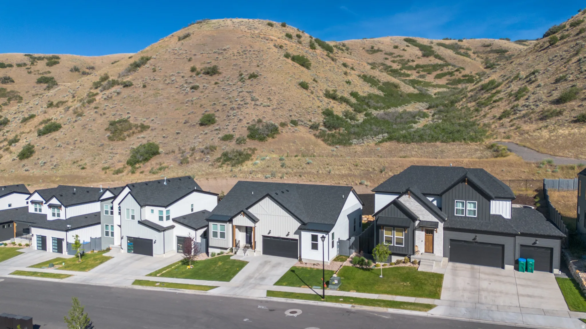 Contemporary residential street featuring multiple homes with varied siding textures and dark asphalt shingle roofs