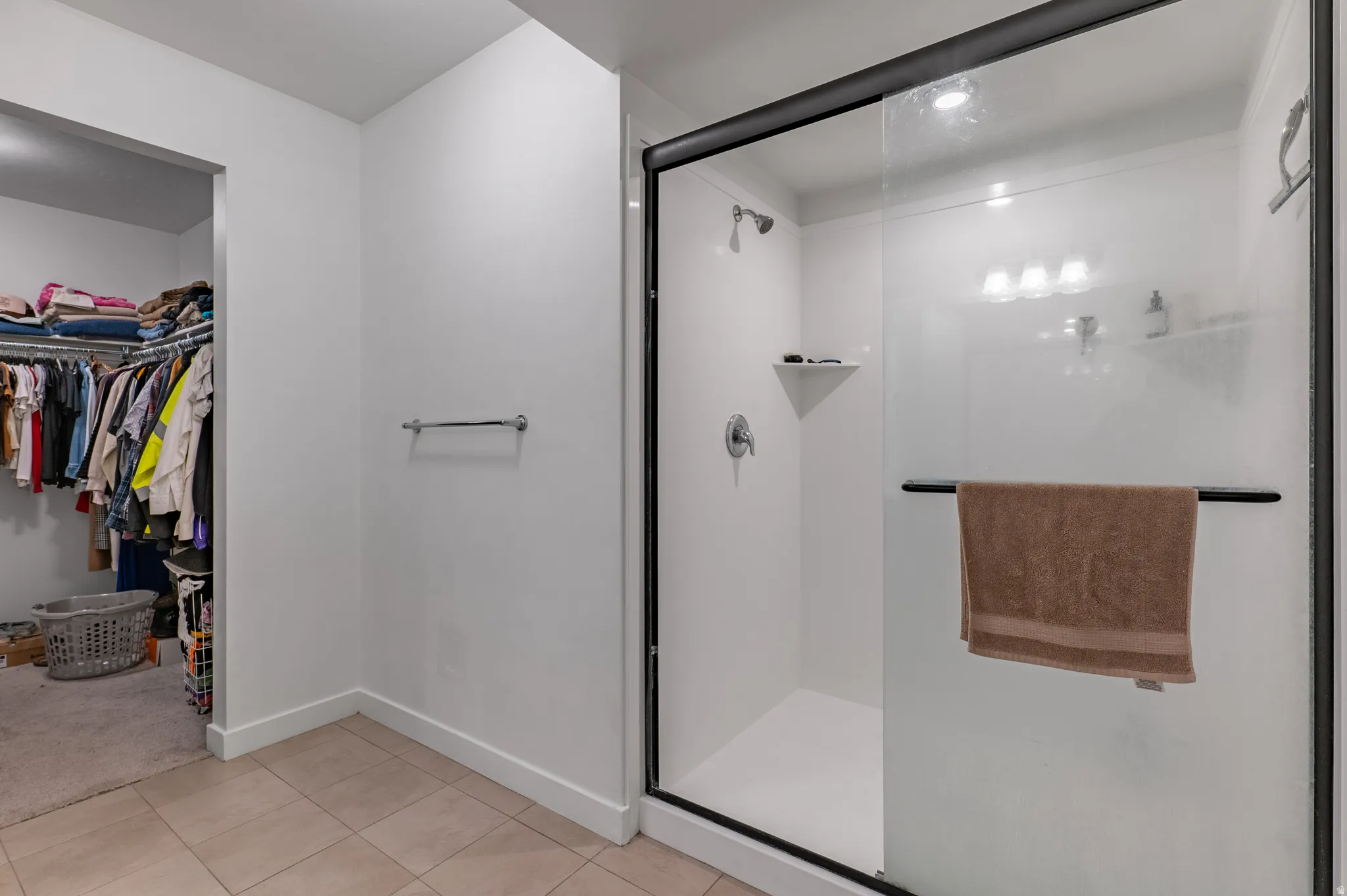 Walk-in shower with a glass enclosure, white paneling, and built-in shelving