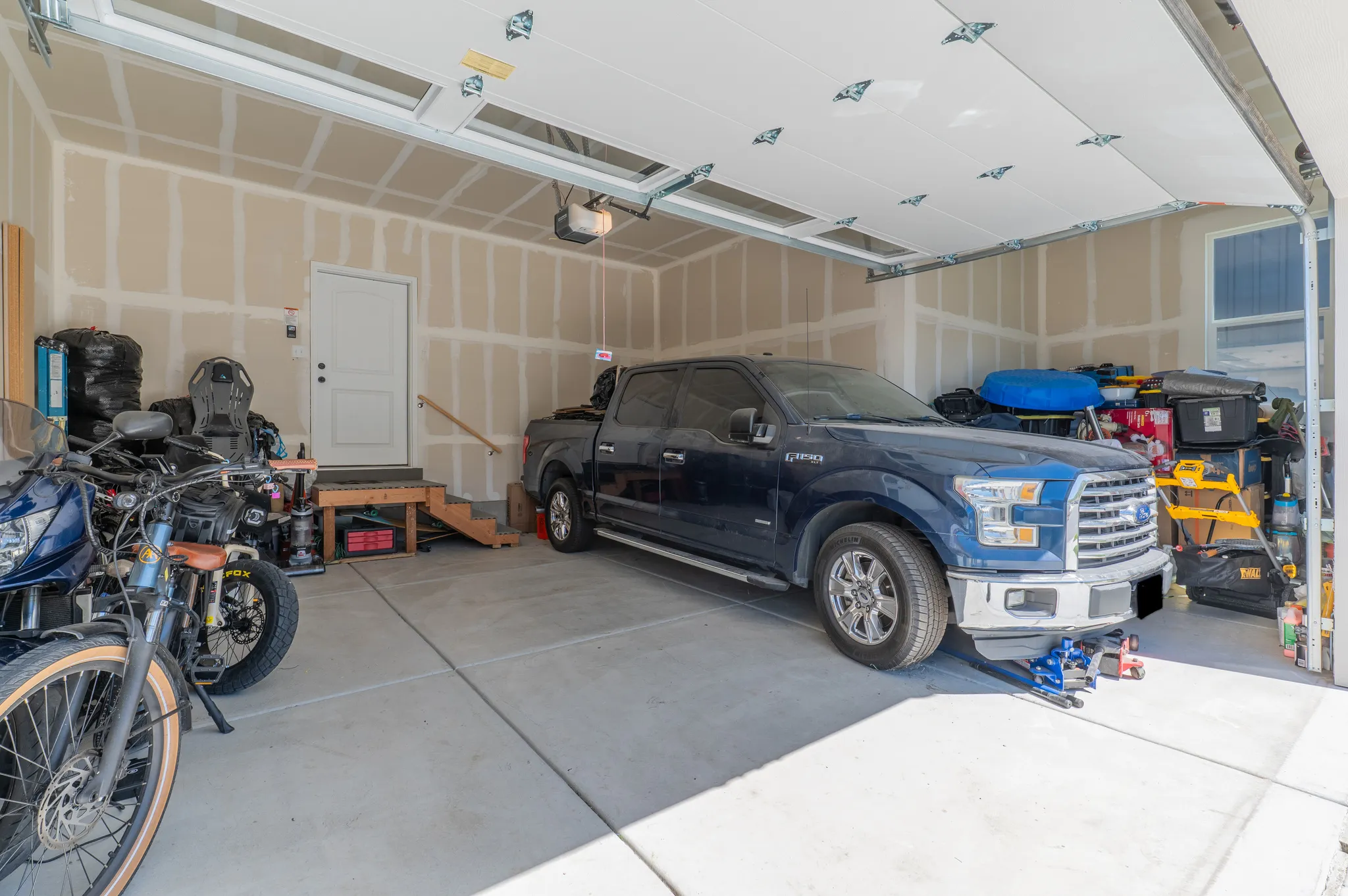 Spacious two-car garage with concrete flooring, automatic garage door opener, and interior access door
