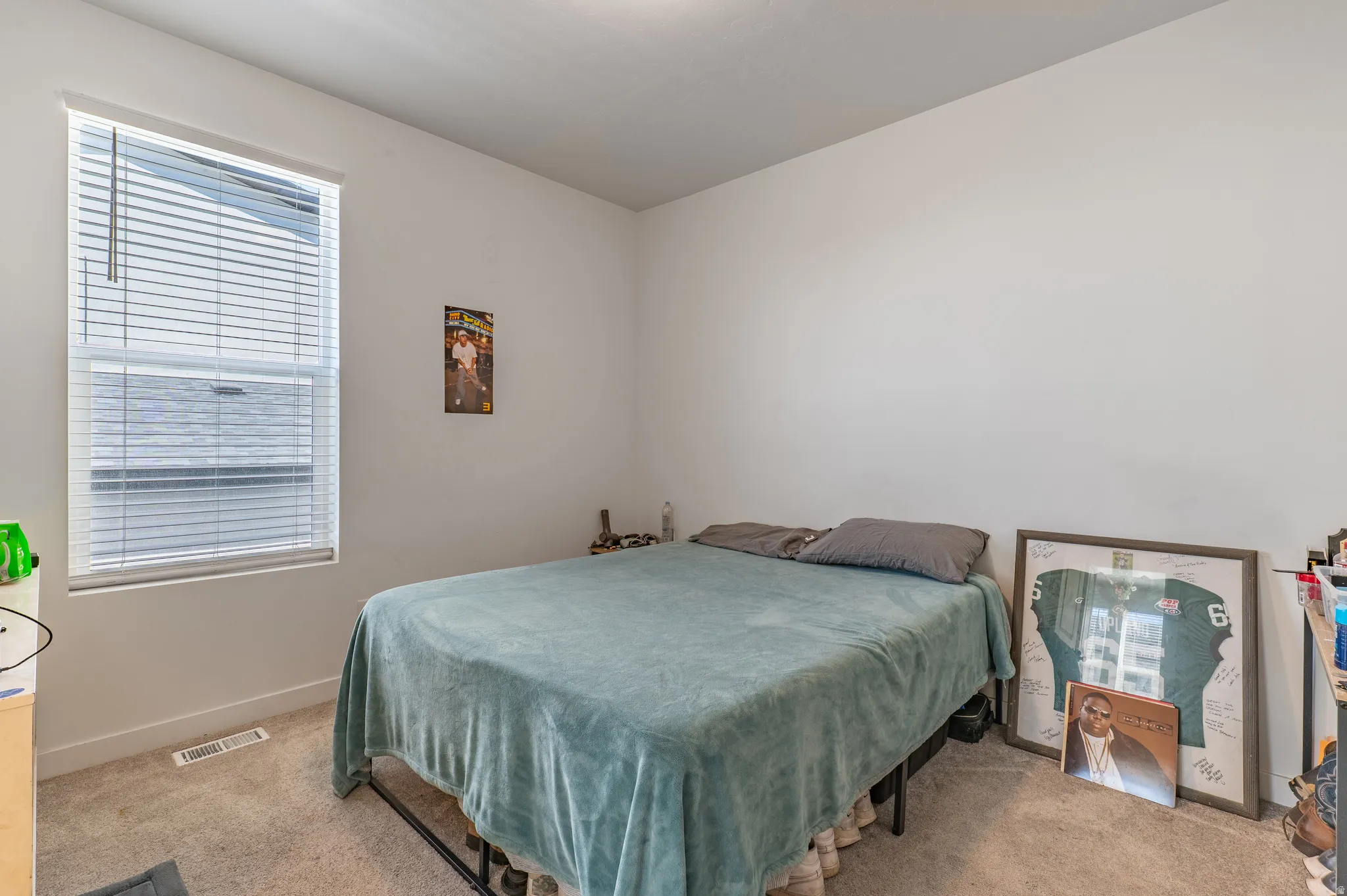 Carpeted room featuring a large window with blinds, white walls, and a ceiling light fixture