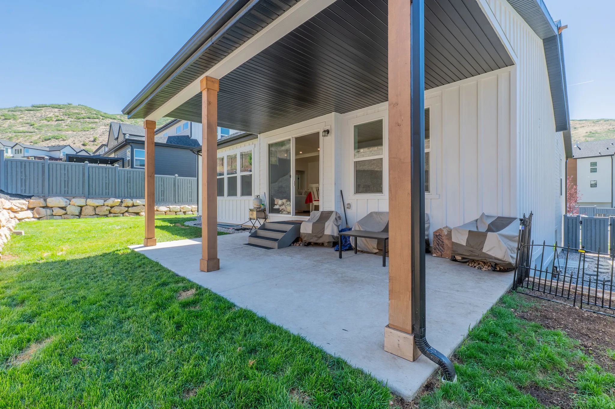 Covered patio featuring a concrete surface, wood-finish support columns, a dark soffit, and access to the interior via a sliding glass door
