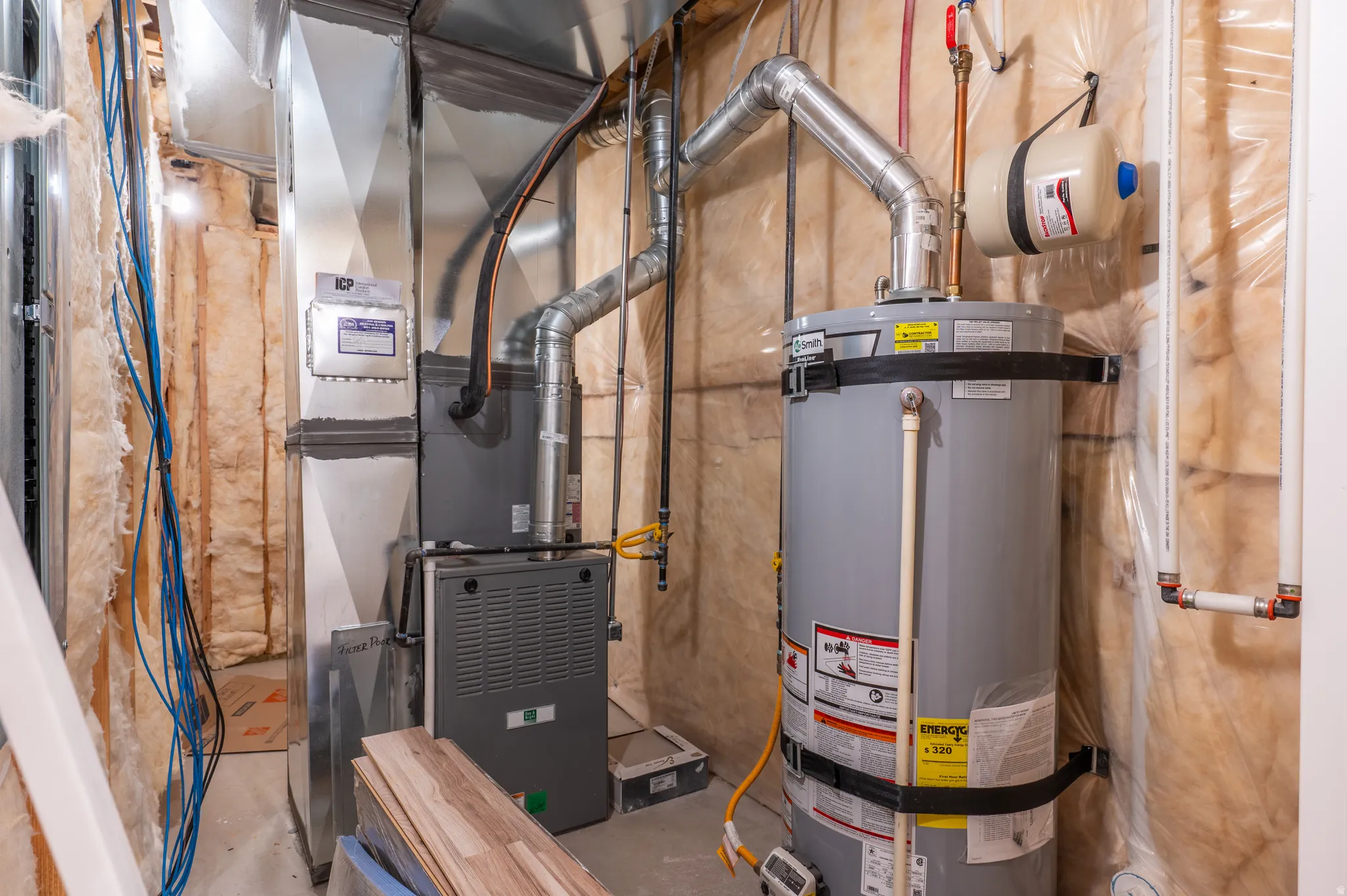 Utility space featuring a water heater, furnace, and exposed ductwork