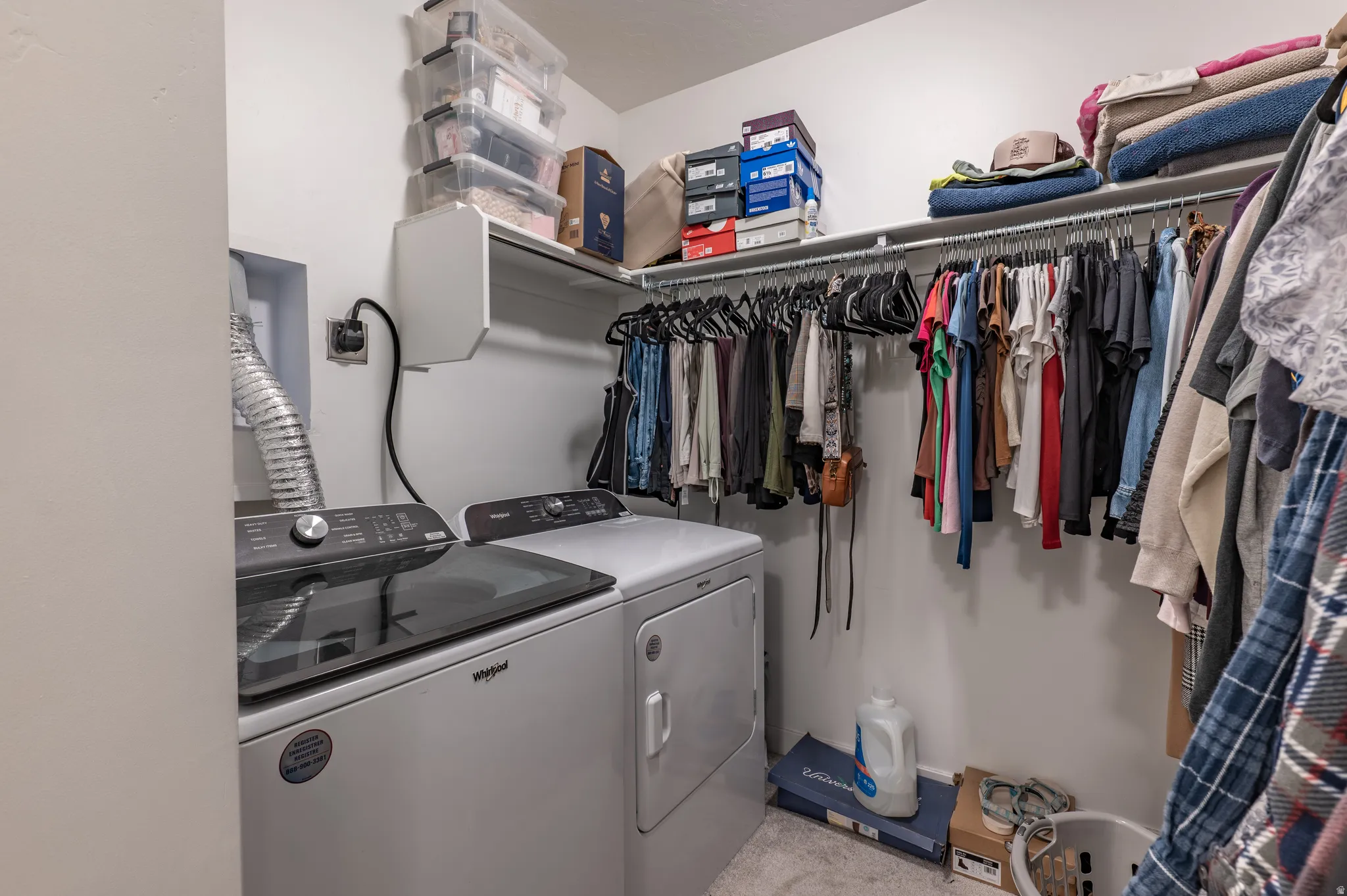 Laundry area integrated into a closet space, featuring a top-load washing machine and a front-load dryer