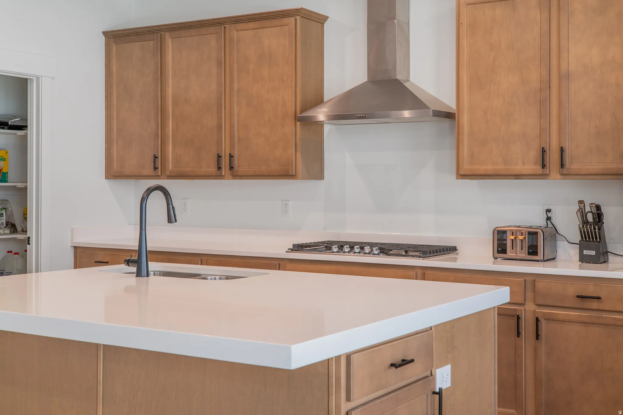 Kitchen island with white countertop and integrated sink, featuring a matte black gooseneck faucet