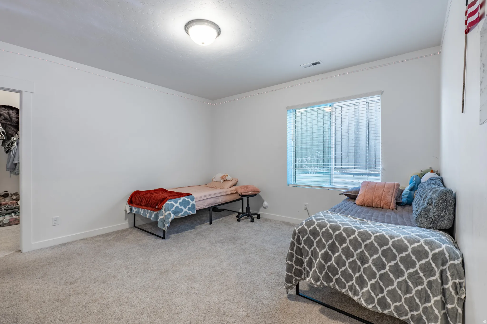 Carpeted room featuring a single window with horizontal blinds, a flush-mount ceiling light fixture, crown molding, and a closet opening