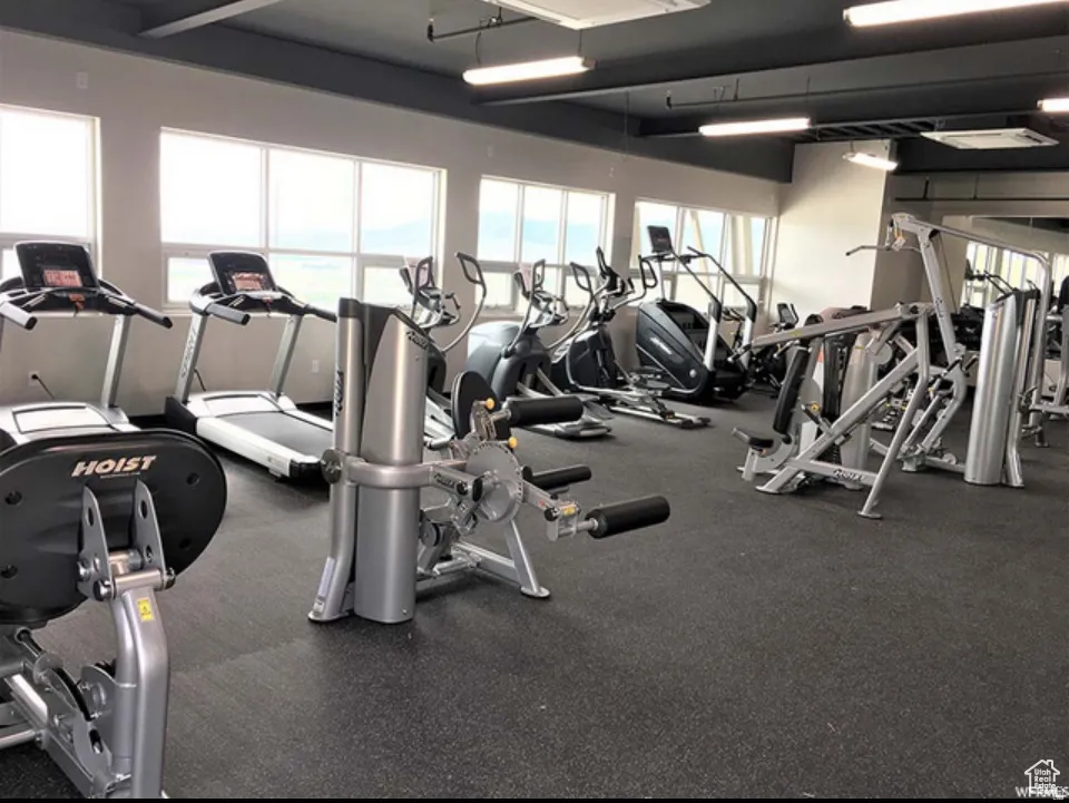 Fitness center featuring multiple exercise machines, expansive window line, high ceilings, recessed lighting, and resilient flooring