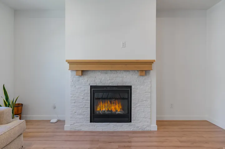 Recessed fireplace featuring a light-toned wood mantel and stacked stone surround
