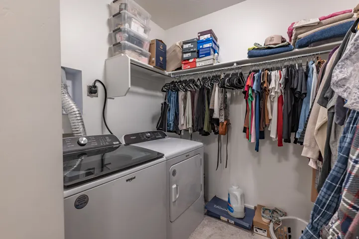 Laundry area integrated into a closet space, featuring a top-load washing machine and a front-load dryer