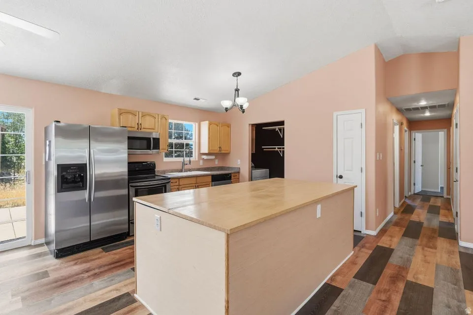 Kitchen featuring a central island with a light wood-finish countertop, stainless steel appliances, and wood-finish flooring