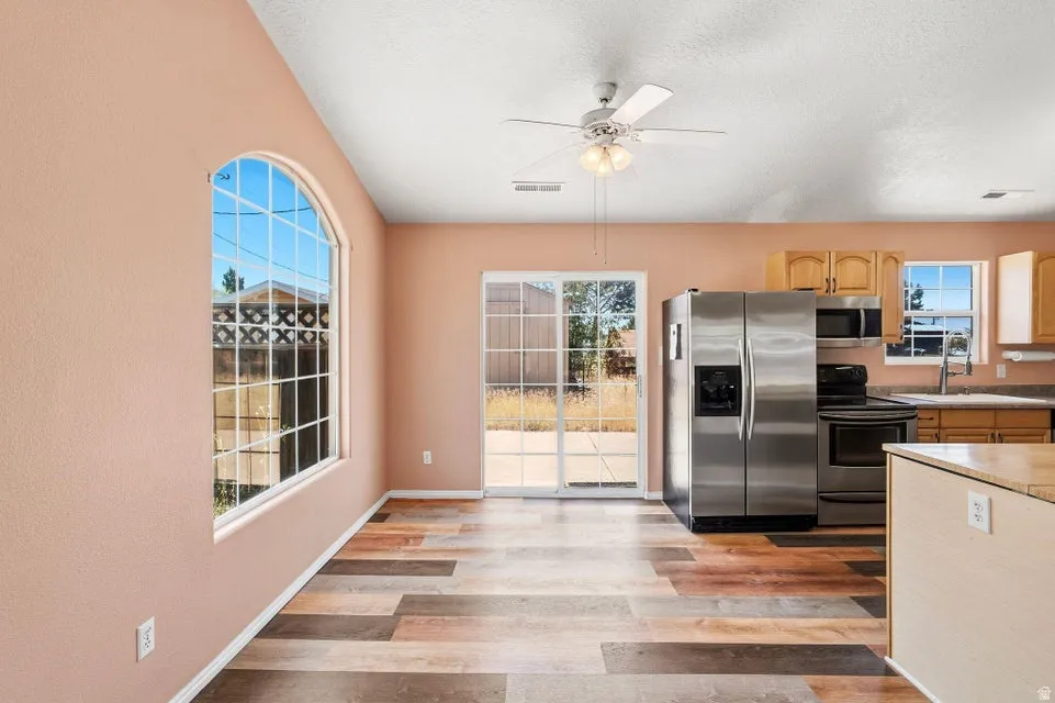 Spacious kitchen and dining area featuring wood-finish flooring and a ceiling fan