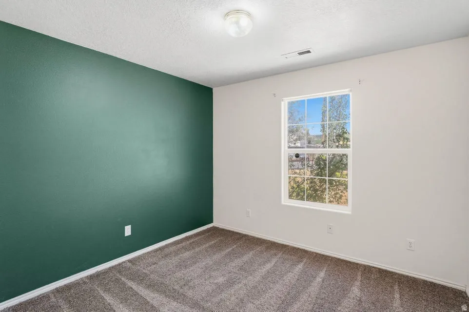 Bedroom featuring a window, textured walls, carpet flooring, baseboards, and a ceiling light fixture
