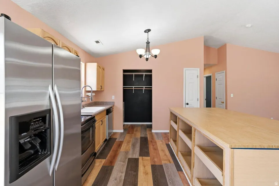 Kitchen with wood-finish flooring, stainless steel side-by-side refrigerator, and light wood cabinetry