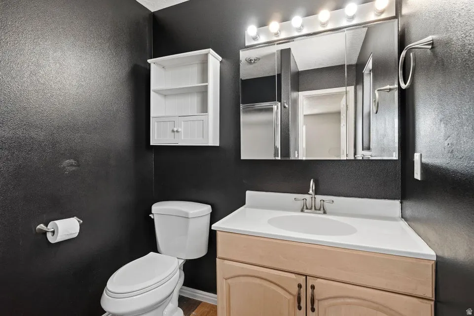 Bathroom featuring a light-toned vanity with a white countertop and integrated sink, brushed nickel faucet, and overhead vanity lighting