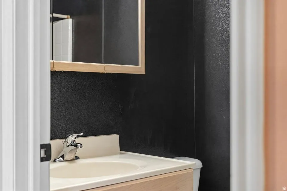 Vanity with integrated sink and chrome faucet, set against a dark textured wall