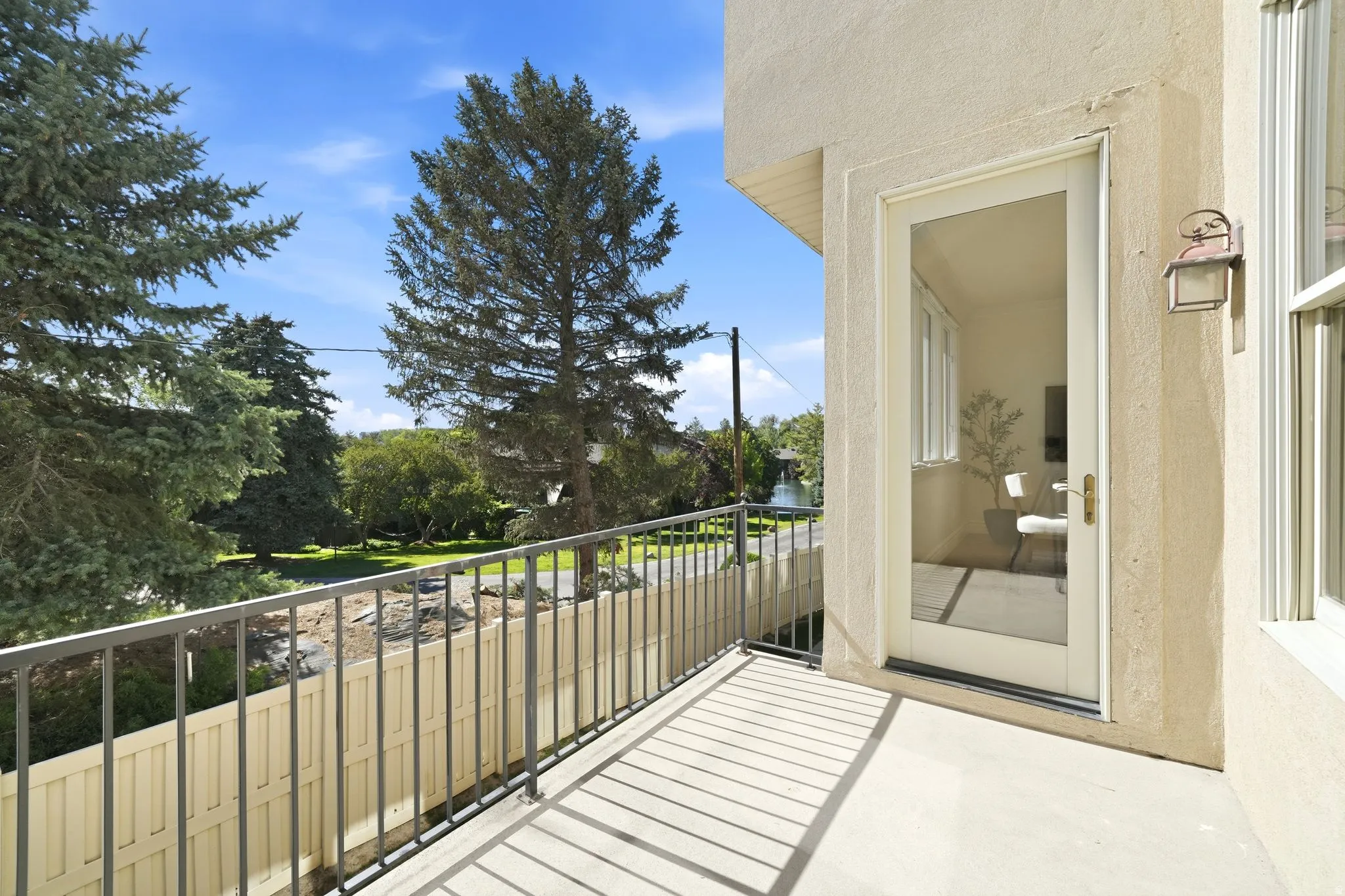 Exterior balcony featuring a stucco finish, metal railing, and a glass-paneled door