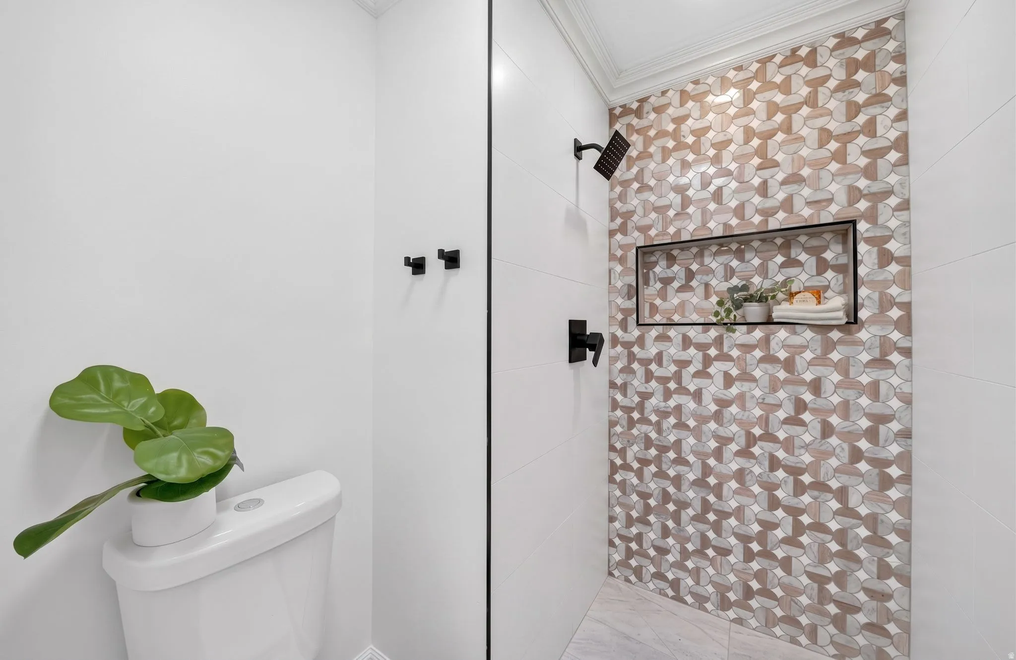 Shower featuring a mosaic tile accent wall, matte black fixtures, and a recessed niche
