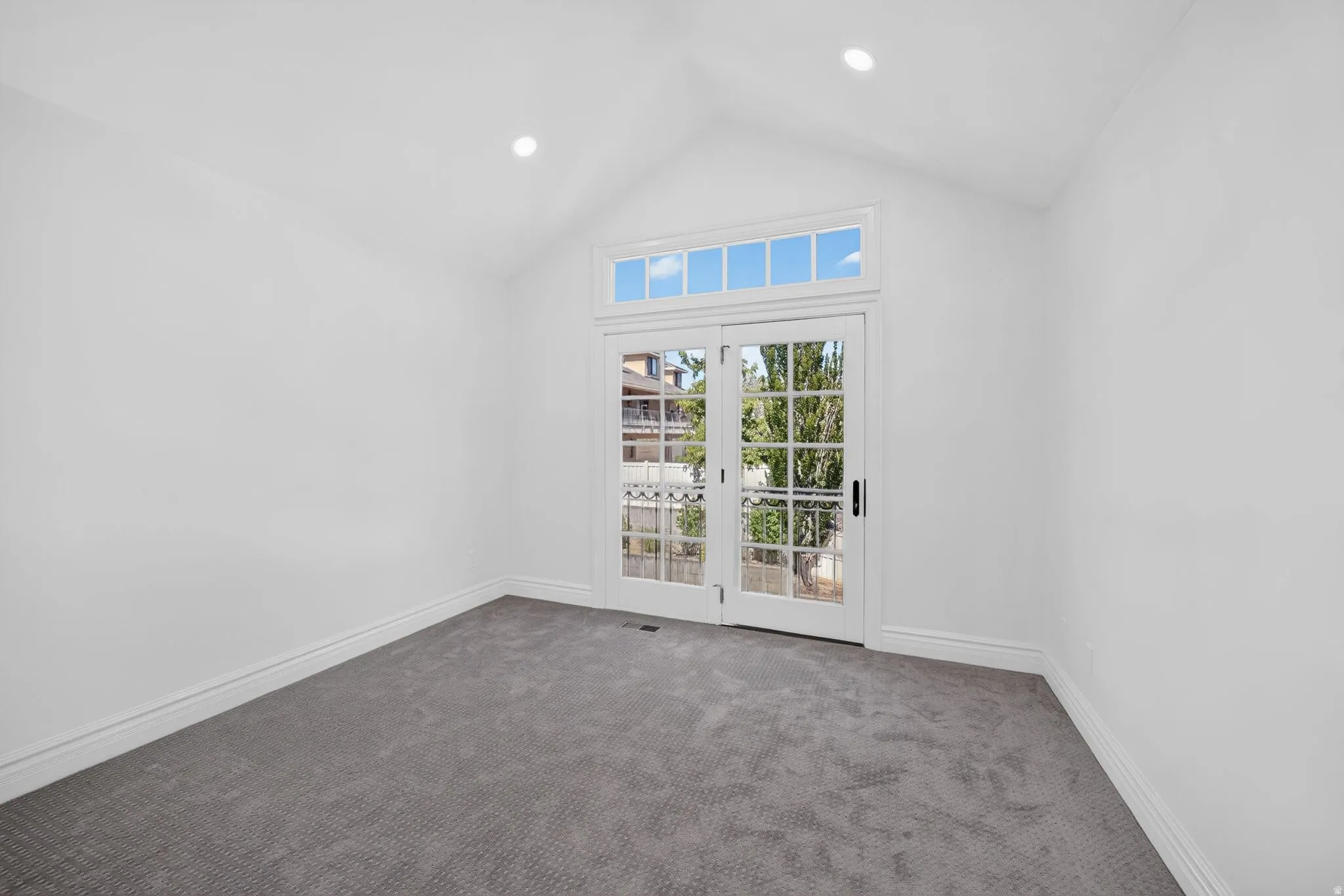 Vaulted ceiling room featuring French doors with transom windows, recessed lighting, white baseboards, and gray patterned carpeting