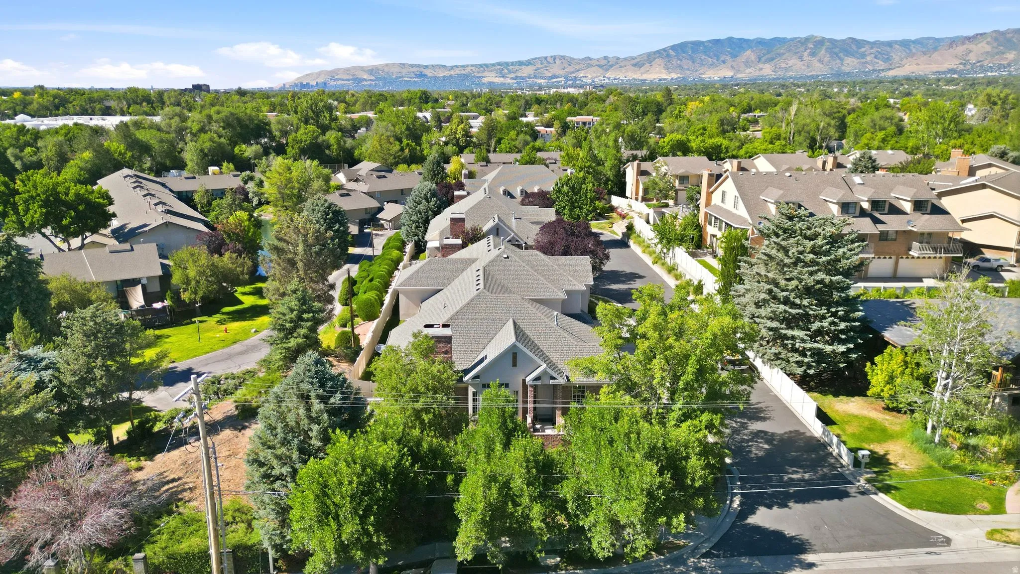 Expansive residential area with mature landscaping, diverse architectural styles, and distant mountain ranges