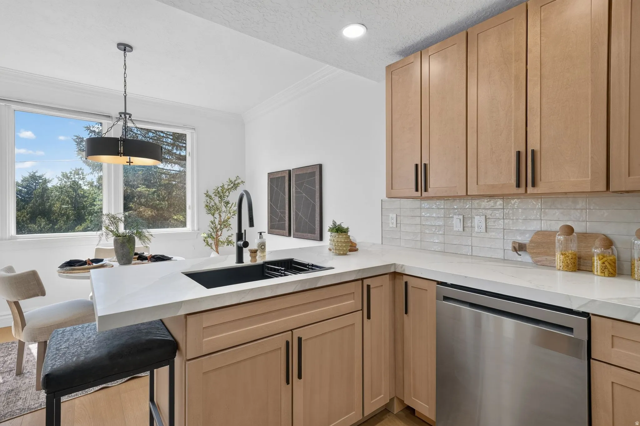 Modern kitchen featuring light wood-finish cabinetry, white countertops, and a subway tile backsplash