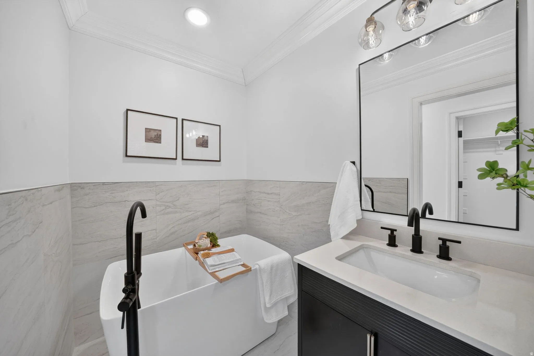 Freestanding soaking tub with a matte black floor-mounted faucet, complemented by a single-sink vanity featuring a white countertop and matte black fixtures