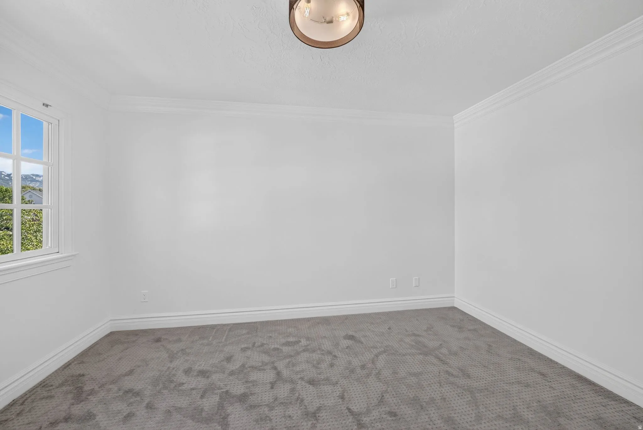 Bright interior space featuring a multi-pane window, crown molding, baseboards, and a semi-flush mount ceiling light