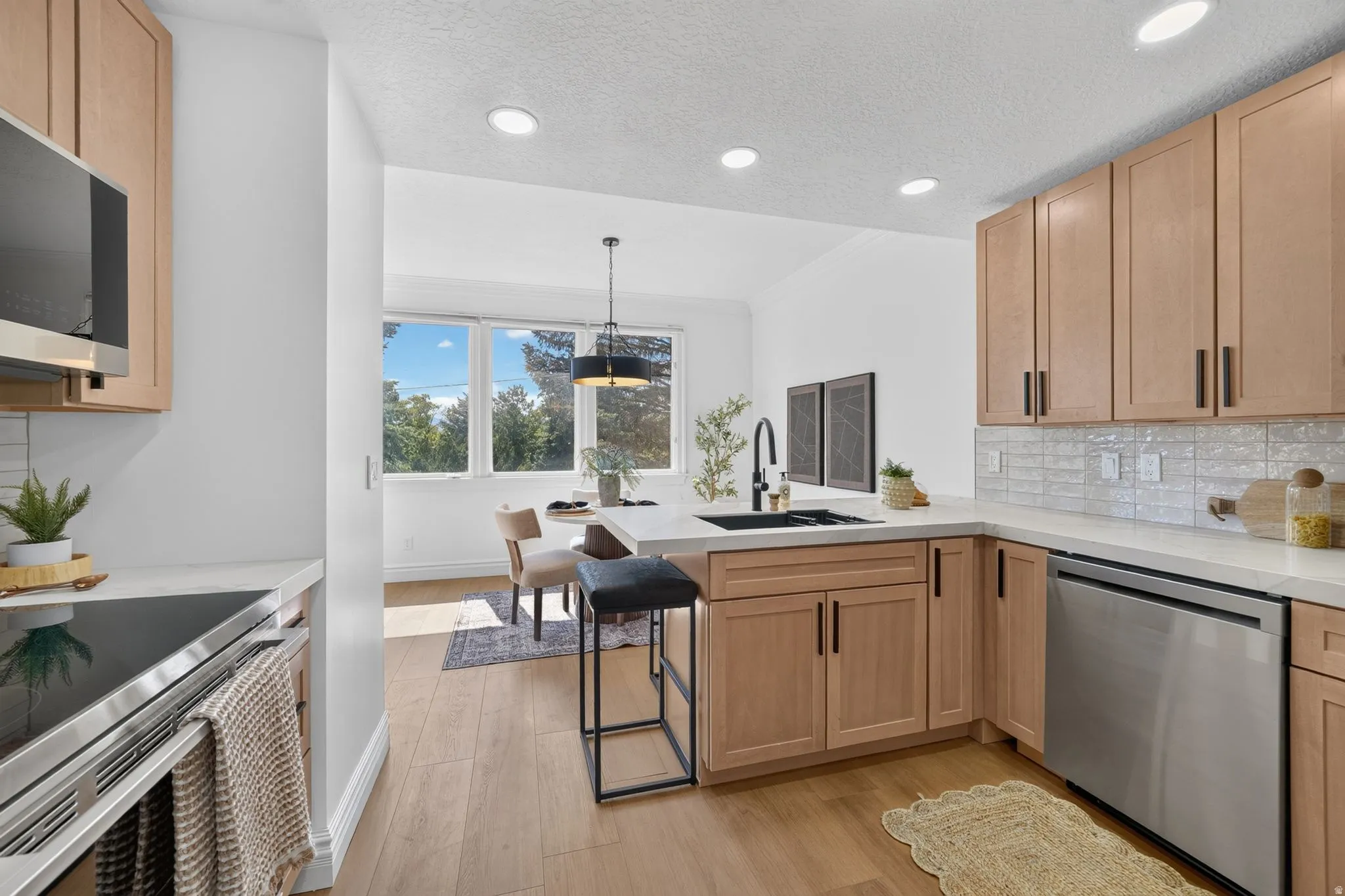 Modern kitchen featuring light wood cabinetry, a white countertop, and stainless steel appliances