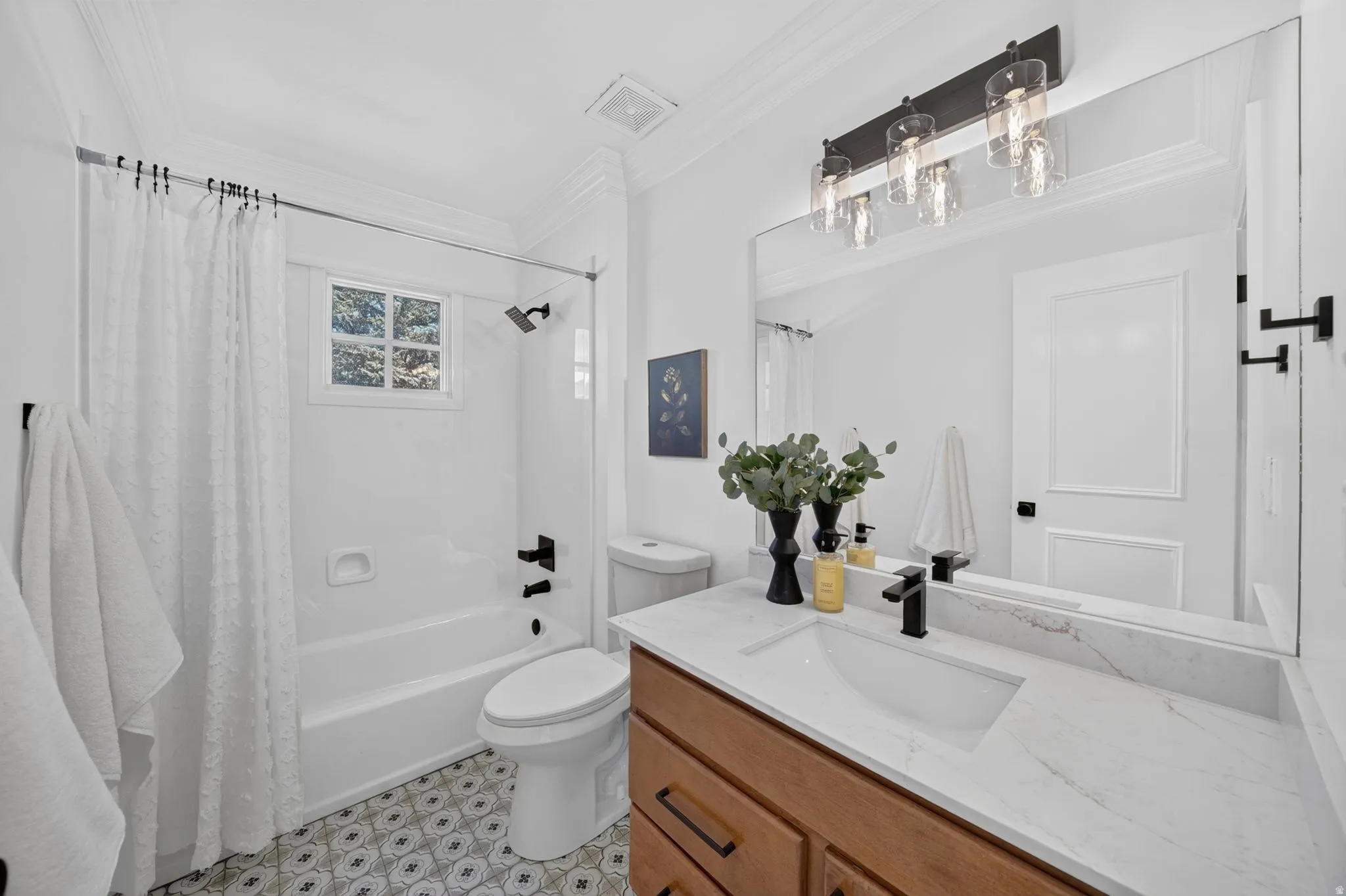Bathroom featuring a wood-finish vanity with a single basin sink, a large wall-mounted mirror, and a three-light vanity fixture