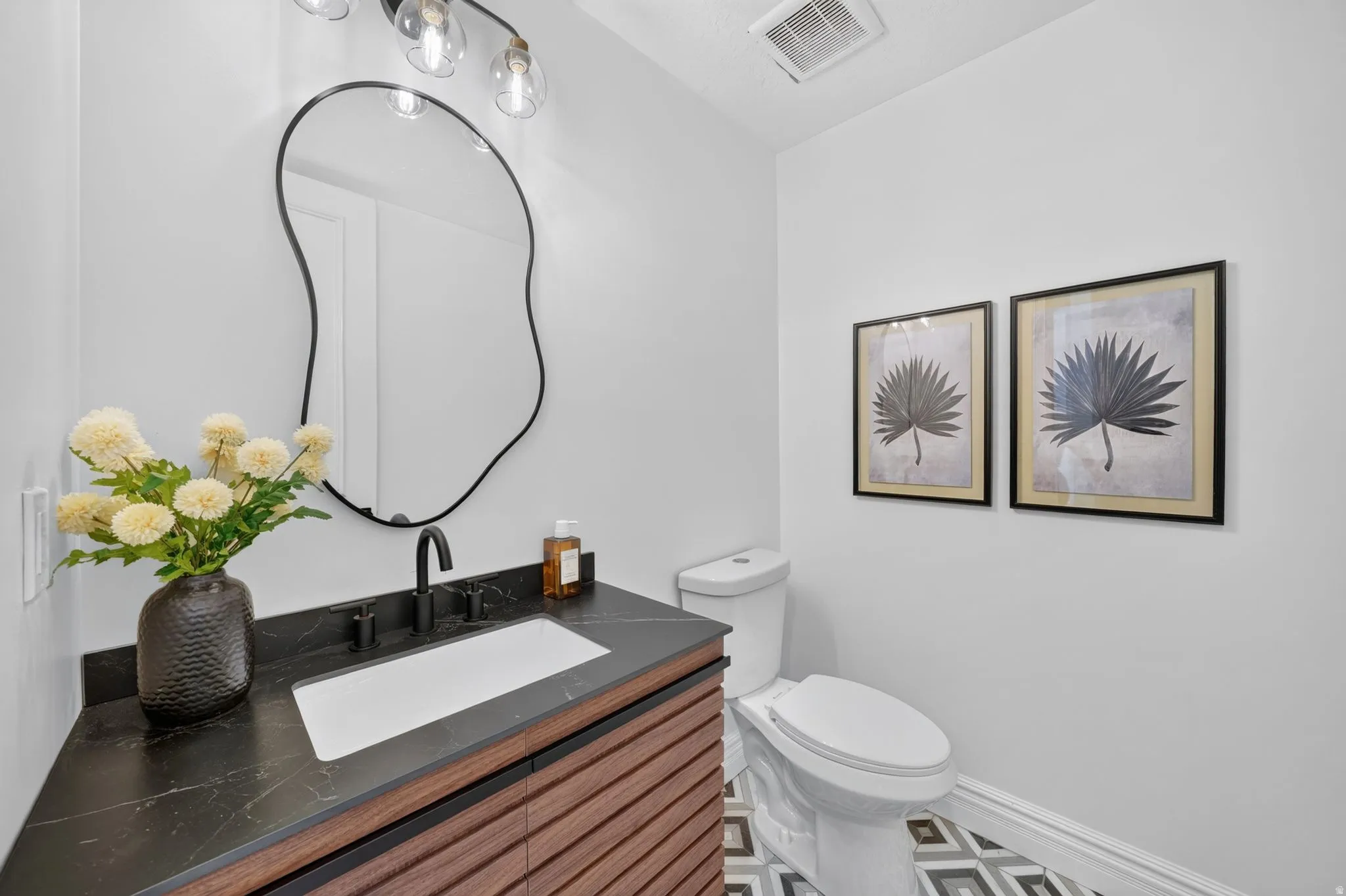 Modern vanity featuring a dark stone countertop, integrated rectangular sink, and matte black faucet