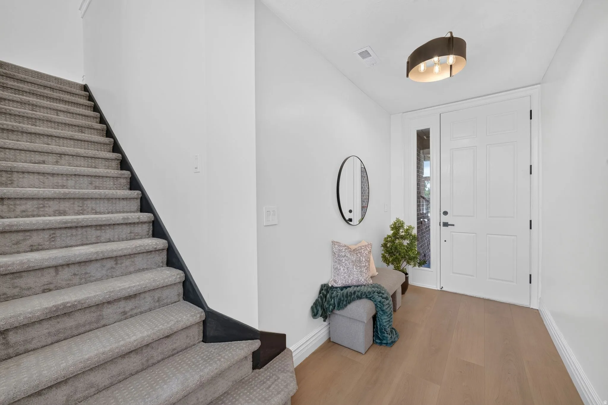 Entryway featuring wood-finish flooring, a contemporary ceiling light fixture, and a white paneled door with a sidelight