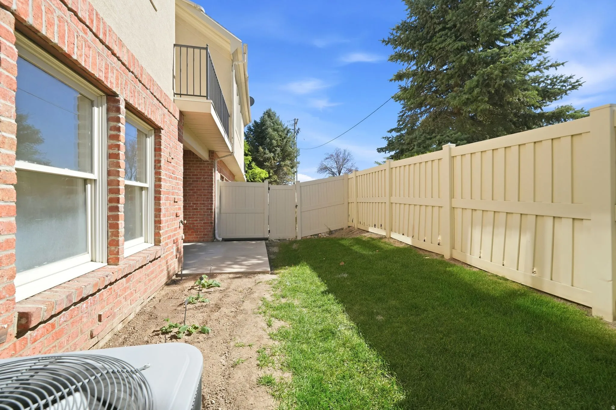 Expansive backyard featuring a manicured lawn and a tall privacy fence with gate access