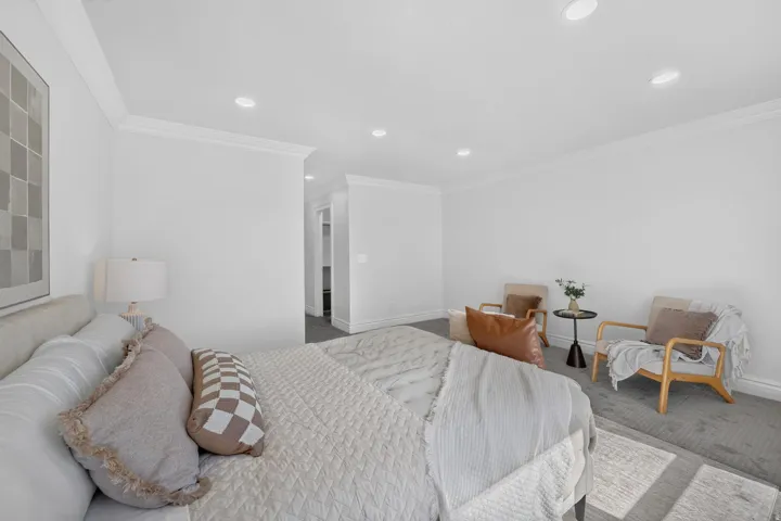 Spacious interior room featuring white walls, crown molding, recessed lighting, and grey carpeting