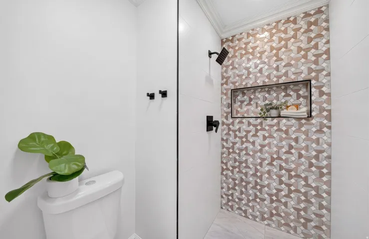 Shower featuring a mosaic tile accent wall, matte black fixtures, and a recessed niche