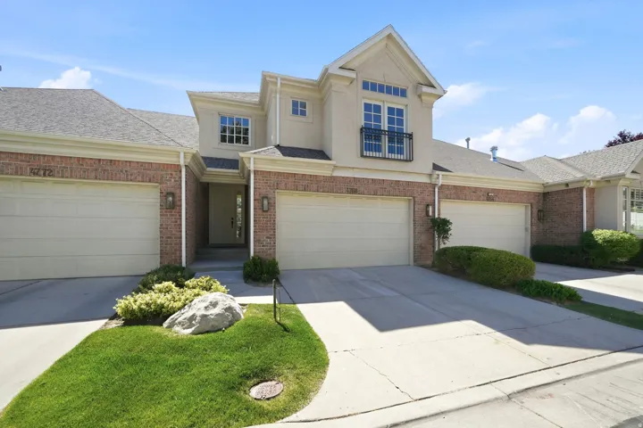 Brick and stucco exterior with multiple garage bays, featuring a second-story balcony with iron railing
