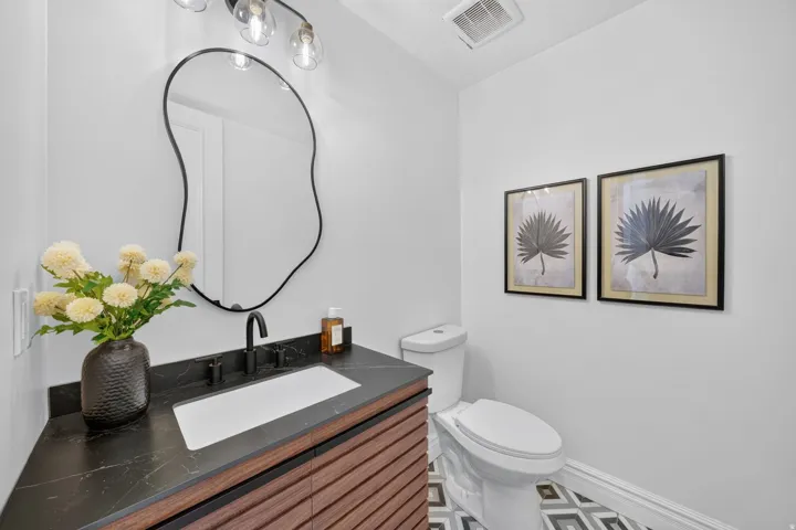 Modern vanity featuring a dark stone countertop, integrated rectangular sink, and matte black faucet