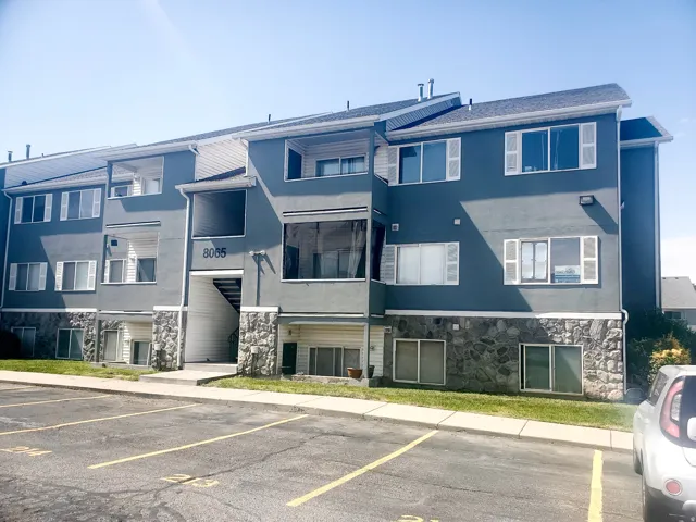 Multi-story building featuring a dark gray stucco exterior with stone veneer accents
