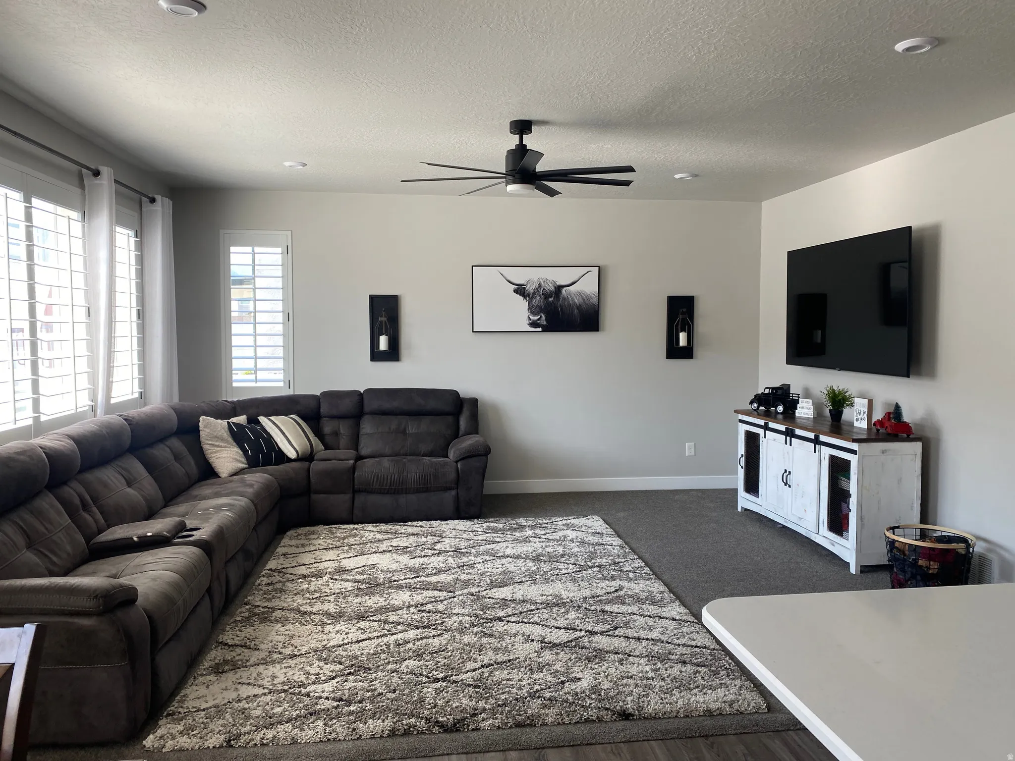 Open-concept living space featuring light gray walls, recessed lighting, and a ceiling fan with matte black blades
