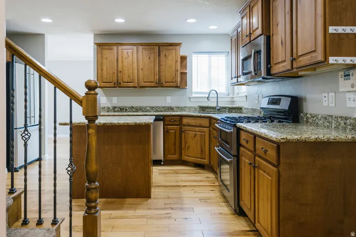 Kitchen featuring wood-finish cabinetry, granite countertops, stainless steel appliances, and recessed lighting
