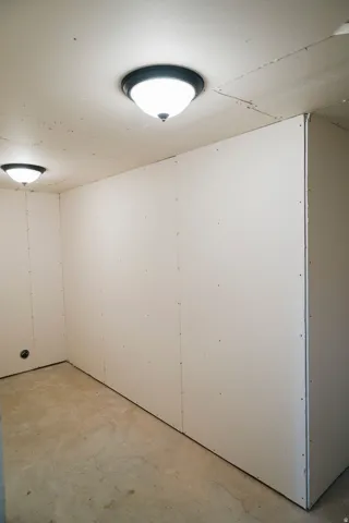 Unfinished interior space featuring drywall paneling, concrete flooring, and two flush-mount ceiling lights