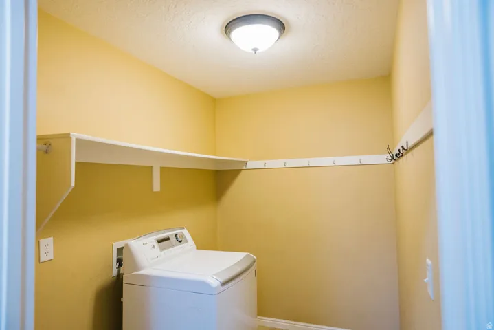 Utility space featuring a built-in shelf, wall-mounted coat hooks, and a ceiling light fixture