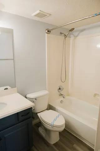 Bathroom featuring a built-in vanity with a white countertop, dark blue cabinetry, a white toilet, and a white bathtub with an integrated shower