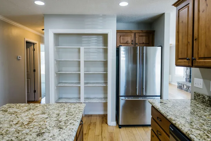 Kitchen featuring light wood-finish flooring, stainless steel French door refrigerator, and granite countertops