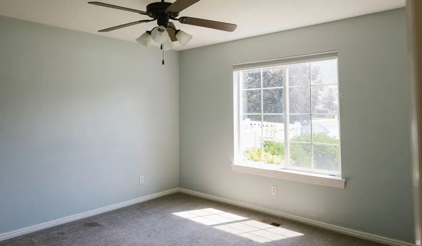 Room featuring light-colored walls, carpeted flooring, and a ceiling fan with integrated lighting
