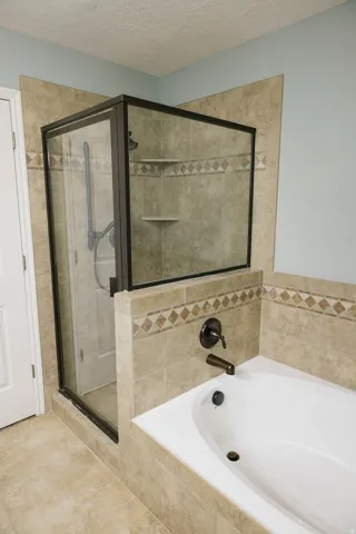 Walk-in shower with dark-framed glass enclosure, integrated shelving, and tiled surround