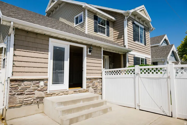Two-story exterior featuring tan siding, stacked stone accents, and a white sliding glass door