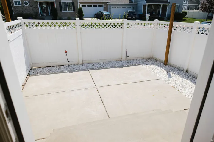 Private patio area featuring a concrete surface, white privacy fencing with lattice accents, and white decorative gravel