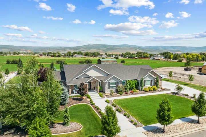 Spacious ranch-style residence featuring a stone and siding exterior, an extended driveway, and mature landscaping