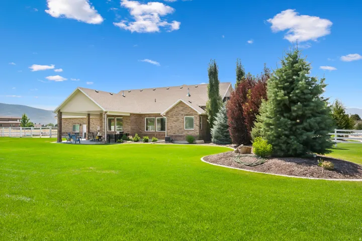 Expansive green lawn with a manicured garden bed featuring mature evergreens